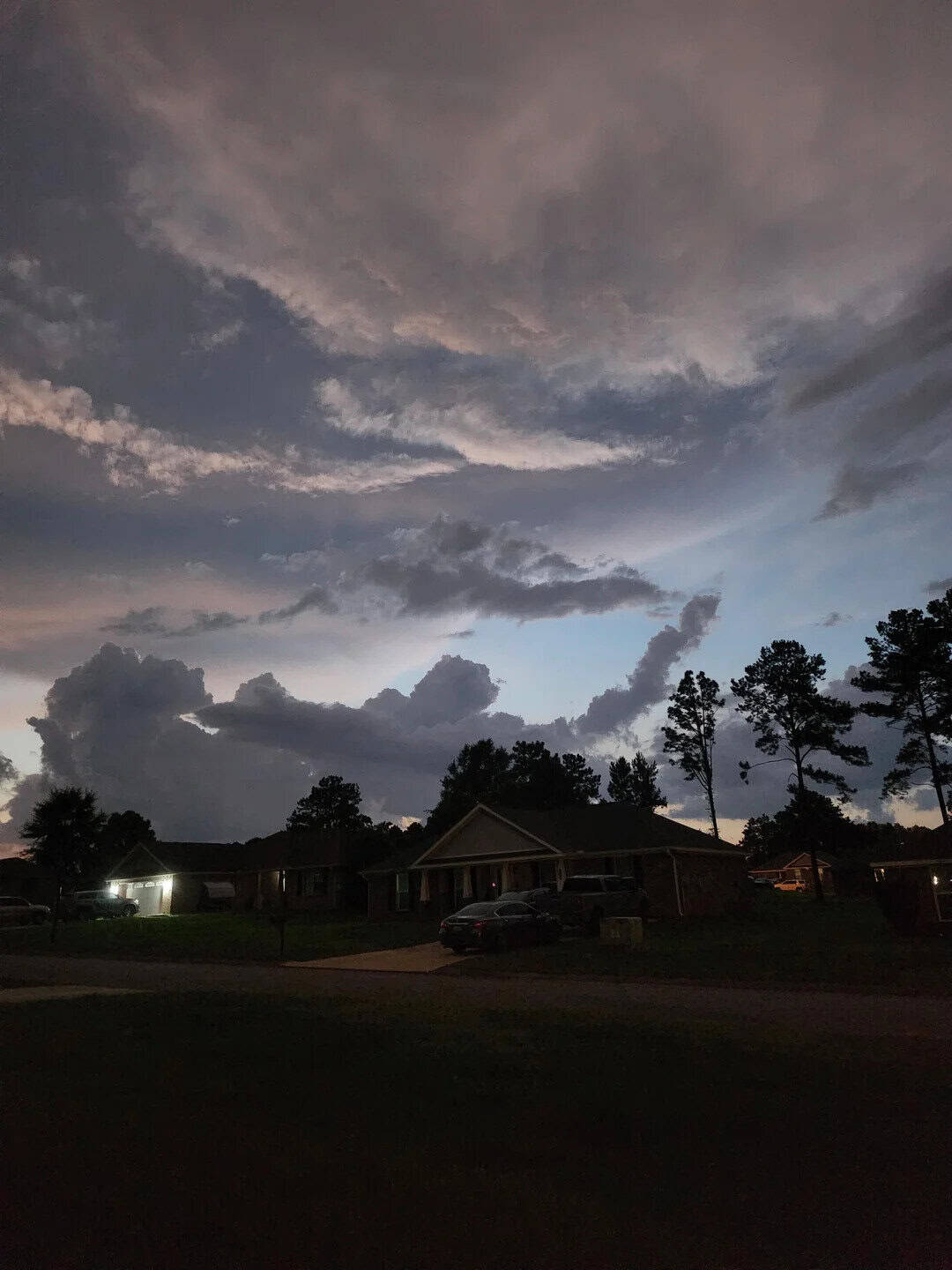 Darkening sky with clouds over suburban neighborhood at dusk.