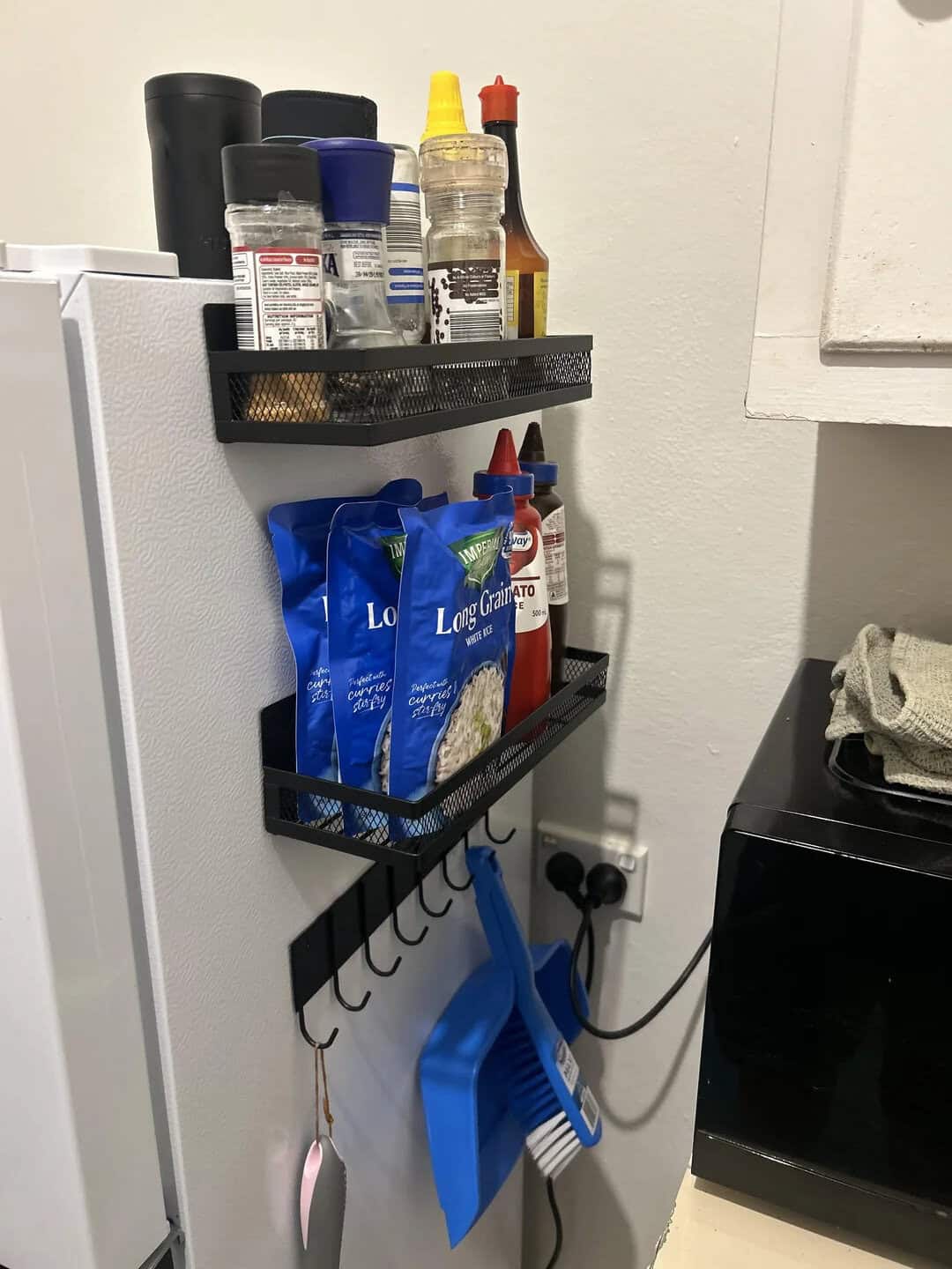 Kitchen spice and condiment rack with sauces, seasonings, and cleaning tools.