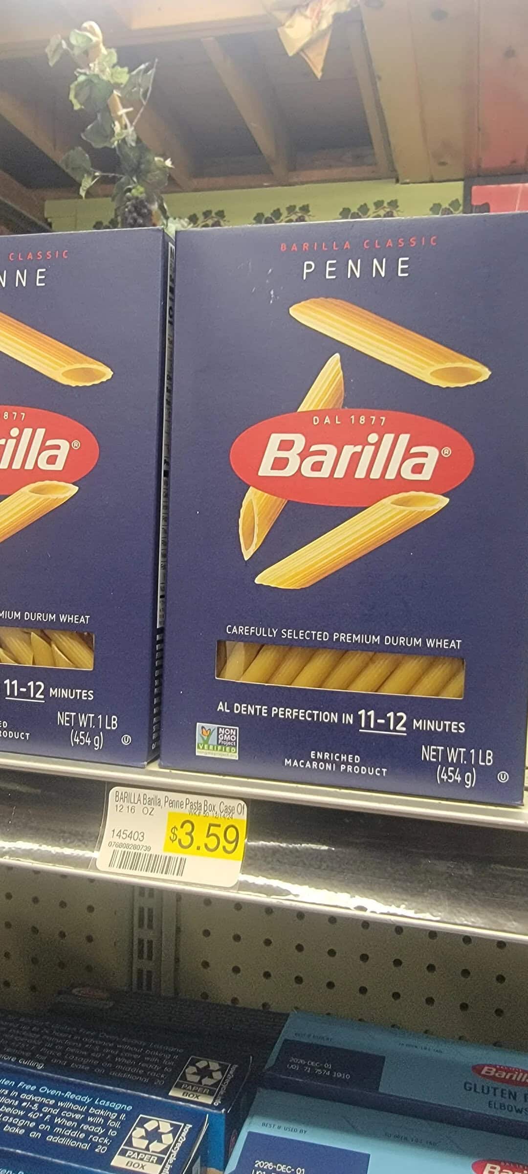 Barilla Penne pasta box on store shelf, price tag $3.59.
