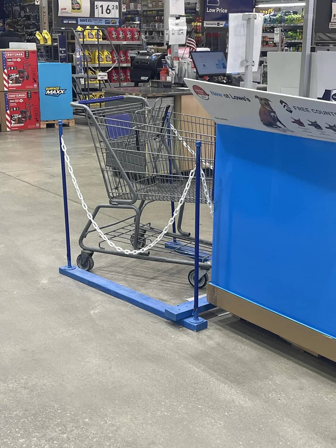 Shopping cart chained to a blue checkout counter at a retail store.