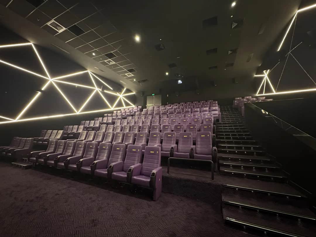 A theater with purple seats and modern lighting on the walls.