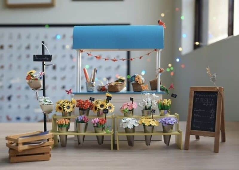 Miniature paper art flower stand with colorful paper flowers and a chalkboard sign.
