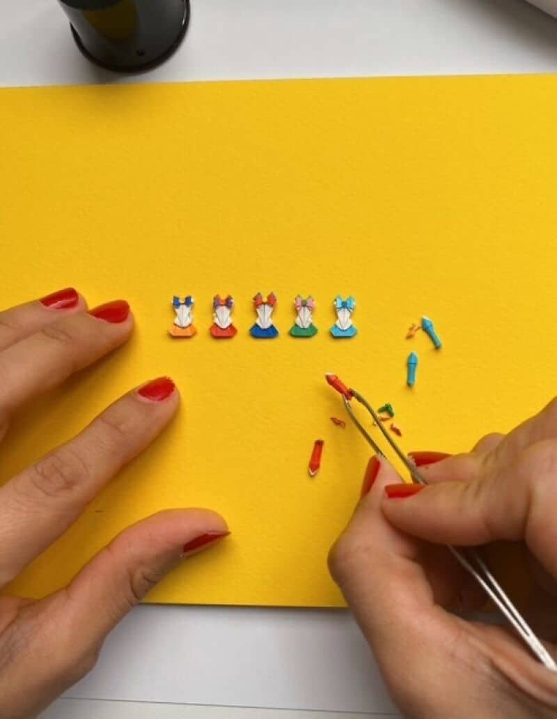 Miniature paper art of colorful dresses on yellow background.