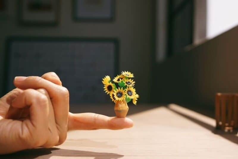 Miniature paper art of a sunflower bouquet on a person's finger.