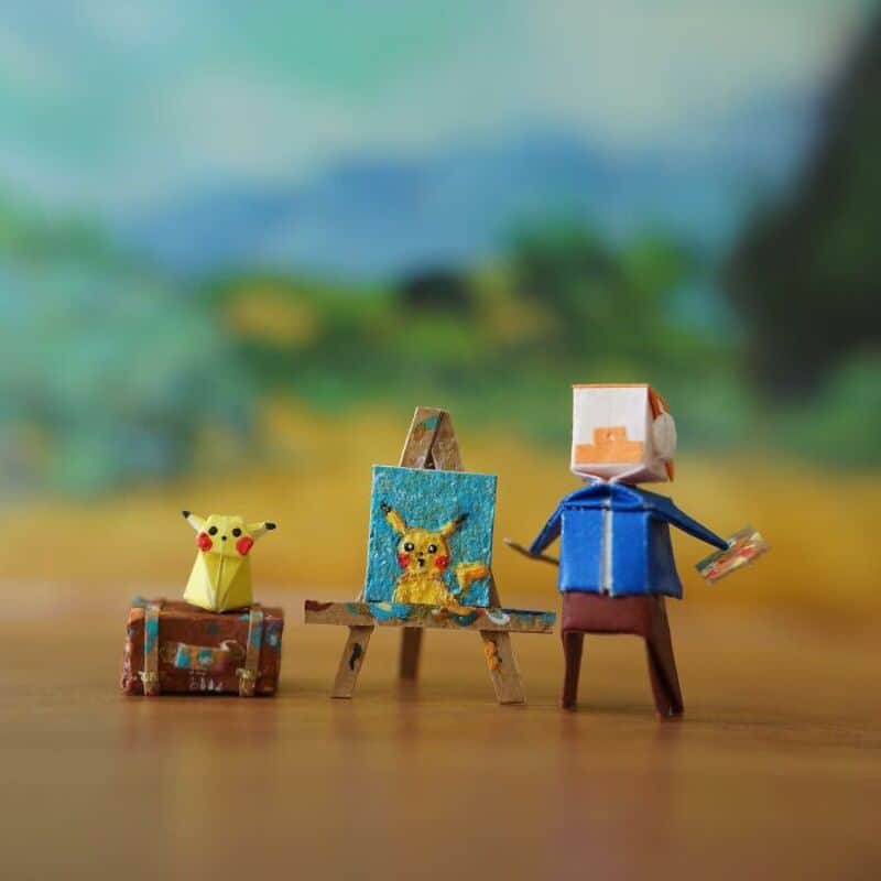 Miniature paper art scene with Pikachu and a person painting a picture.