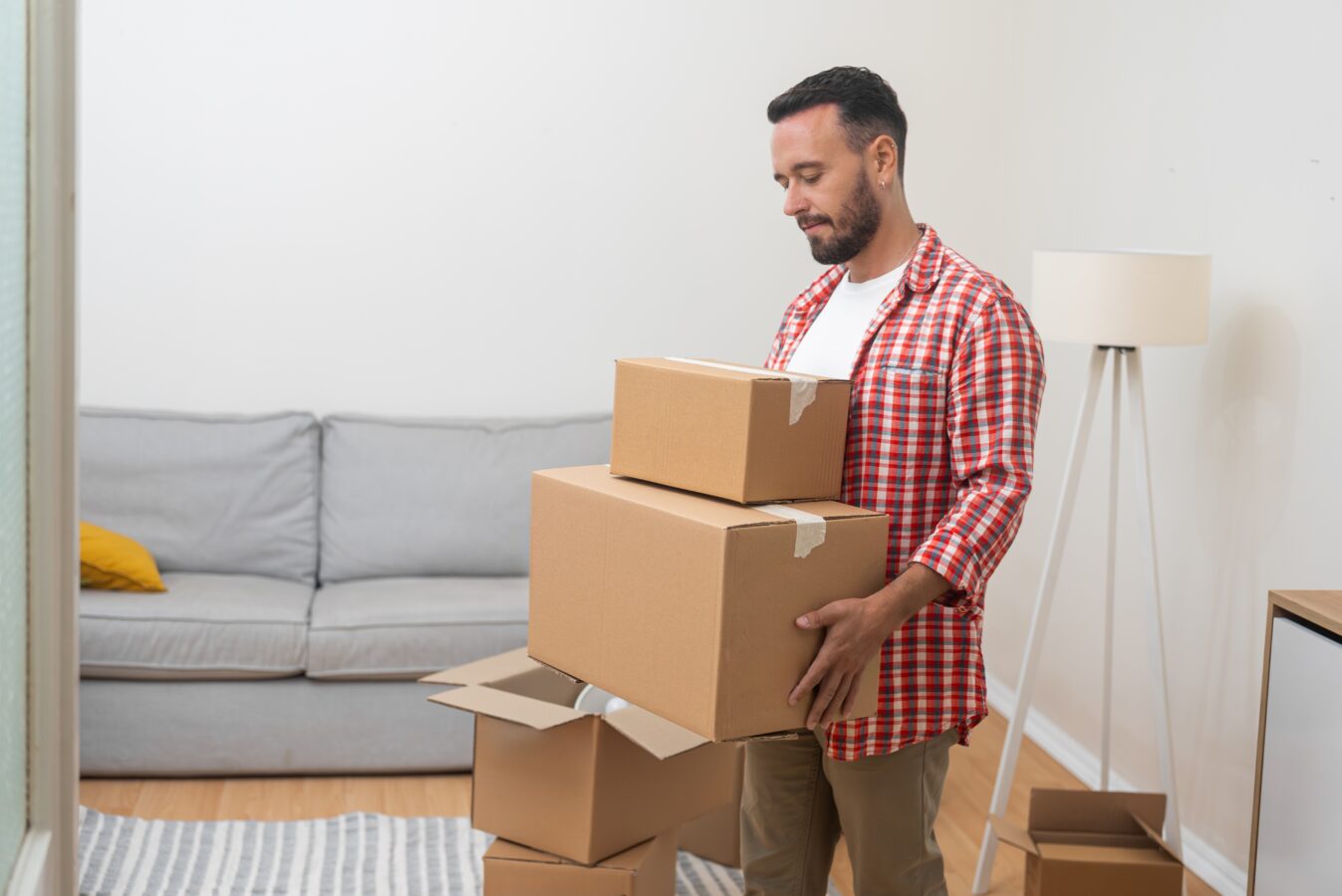 Moving man holding boxes in living room.