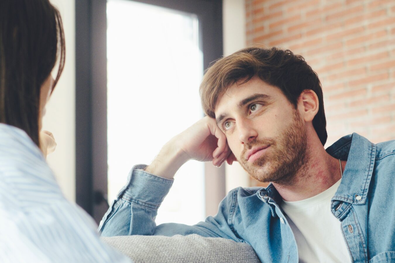 A young man listening attentively during a conversation with a woman.