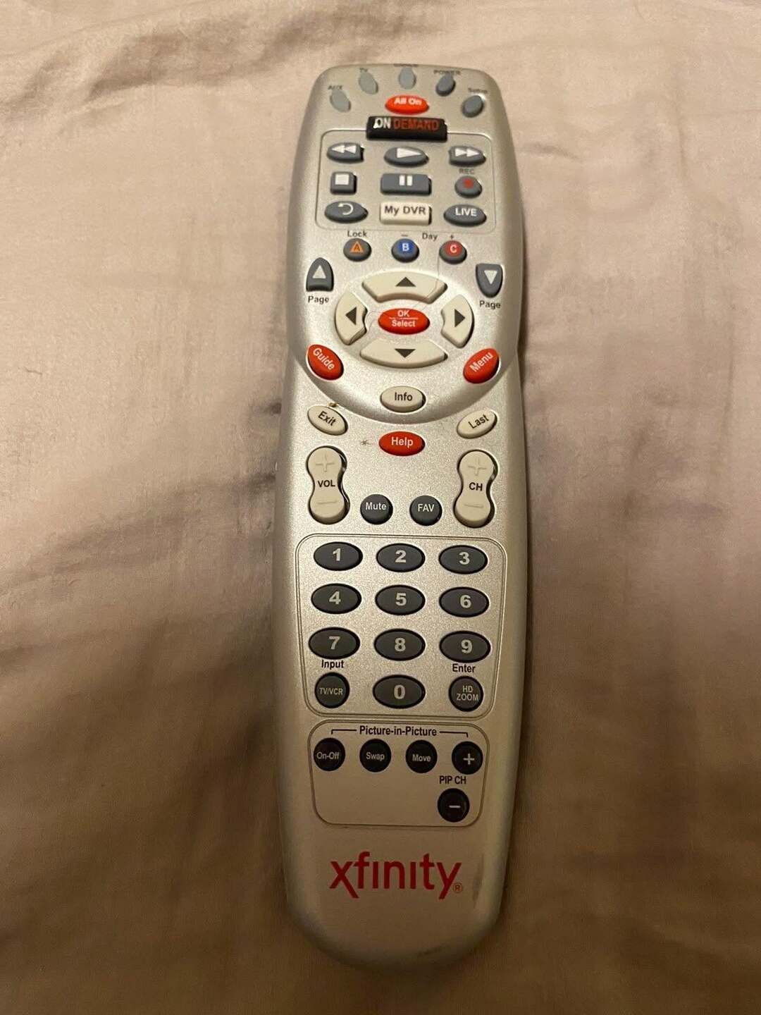 Xfinity remote control on beige fabric background.