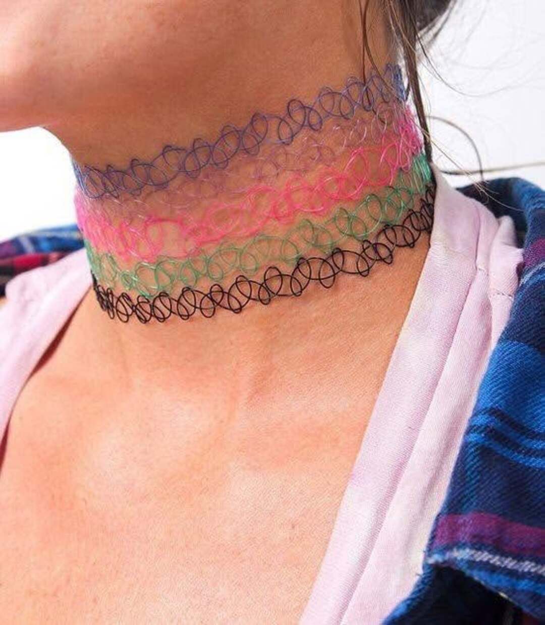 Colorful layered choker necklaces on a person's neck, with a pink, green, and black design.