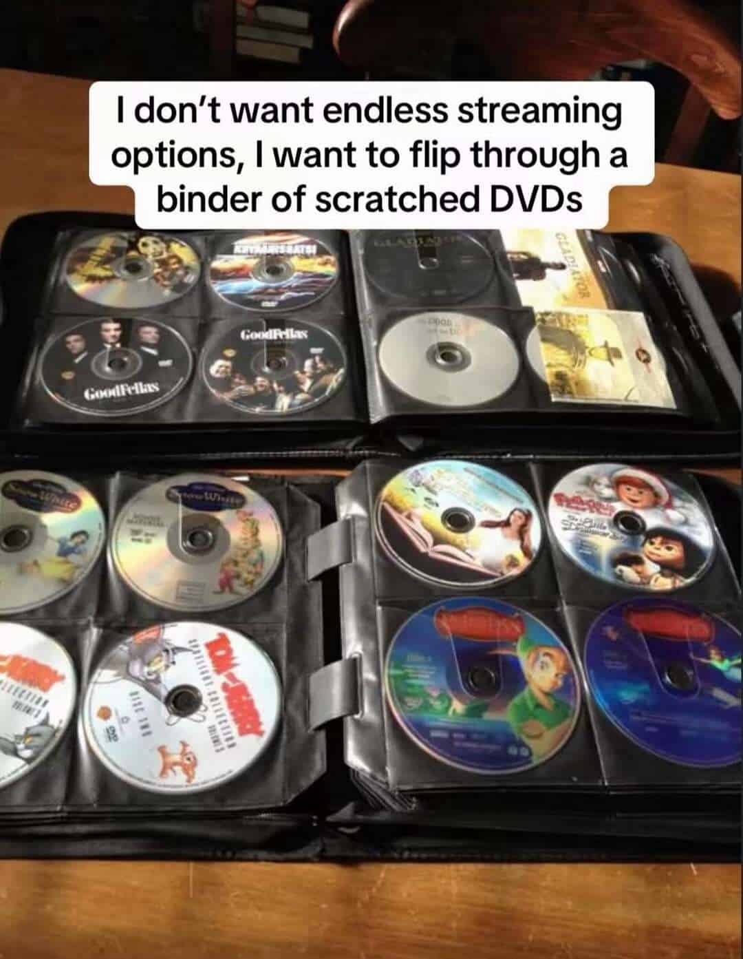 Collection of DVDs in a binder with a quote about preferring scratched DVDs over streaming.