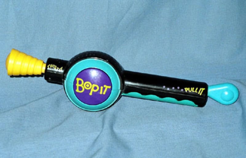 Bop It toy with yellow, black, and blue parts on a blue fabric background.