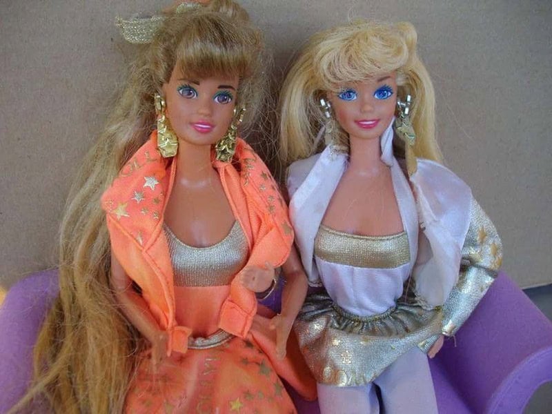 Two vintage Barbie dolls with blonde hair, dressed in colorful 80s-style outfits.