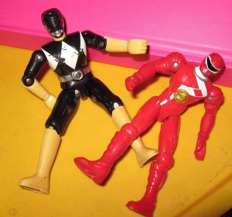 Black and white and red Power Rangers action figures on a yellow and pink background.