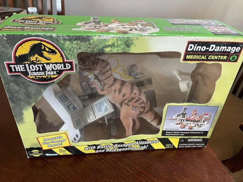 The Lost World Jurassic Park Dino-Damage toy box with dinosaur and accessories inside.