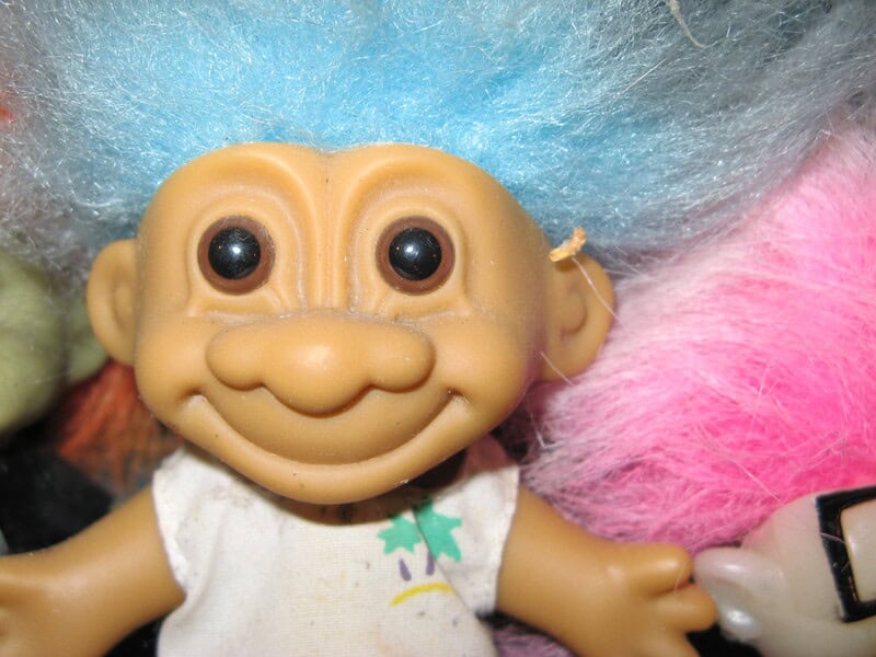 Close-up of a vintage troll doll with a smiling face, big eyes, and colorful hair.