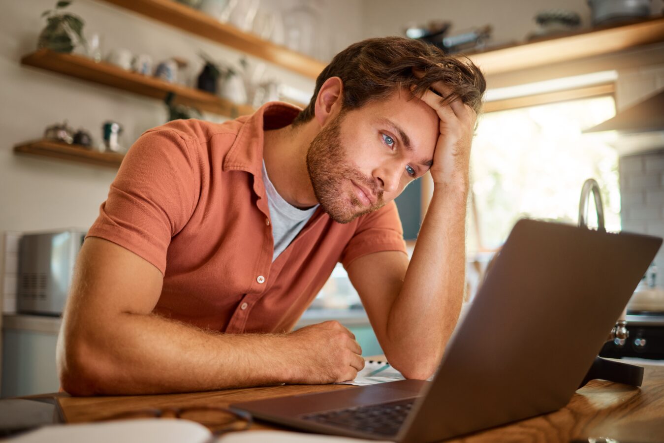 Feeling stressed while working on a laptop at home.