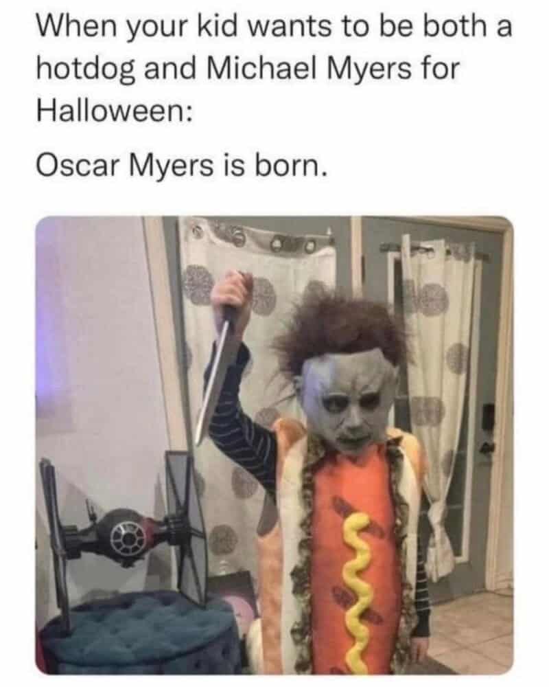 Child dressed as a hotdog with a zombie face, holding a toy sword.