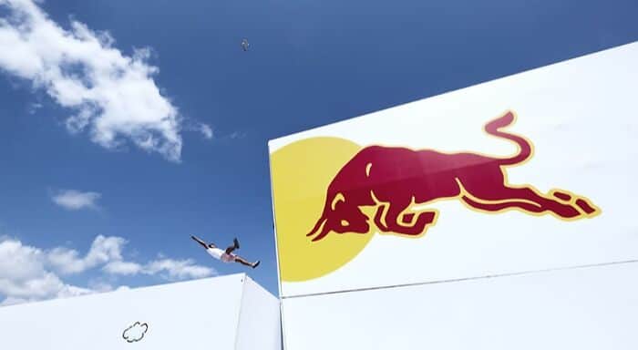 Red Bull logo with a person skydiving in the background.
