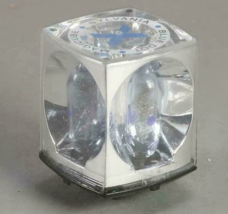 A clear cube with a blue and white label on top, containing two oval-shaped objects inside.