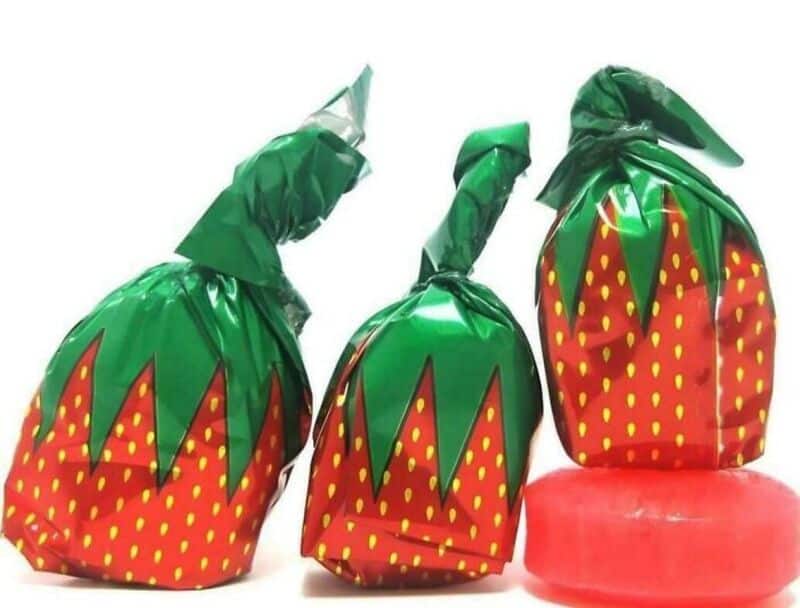 Three strawberry-shaped candies wrapped in green and red foil with yellow dots.