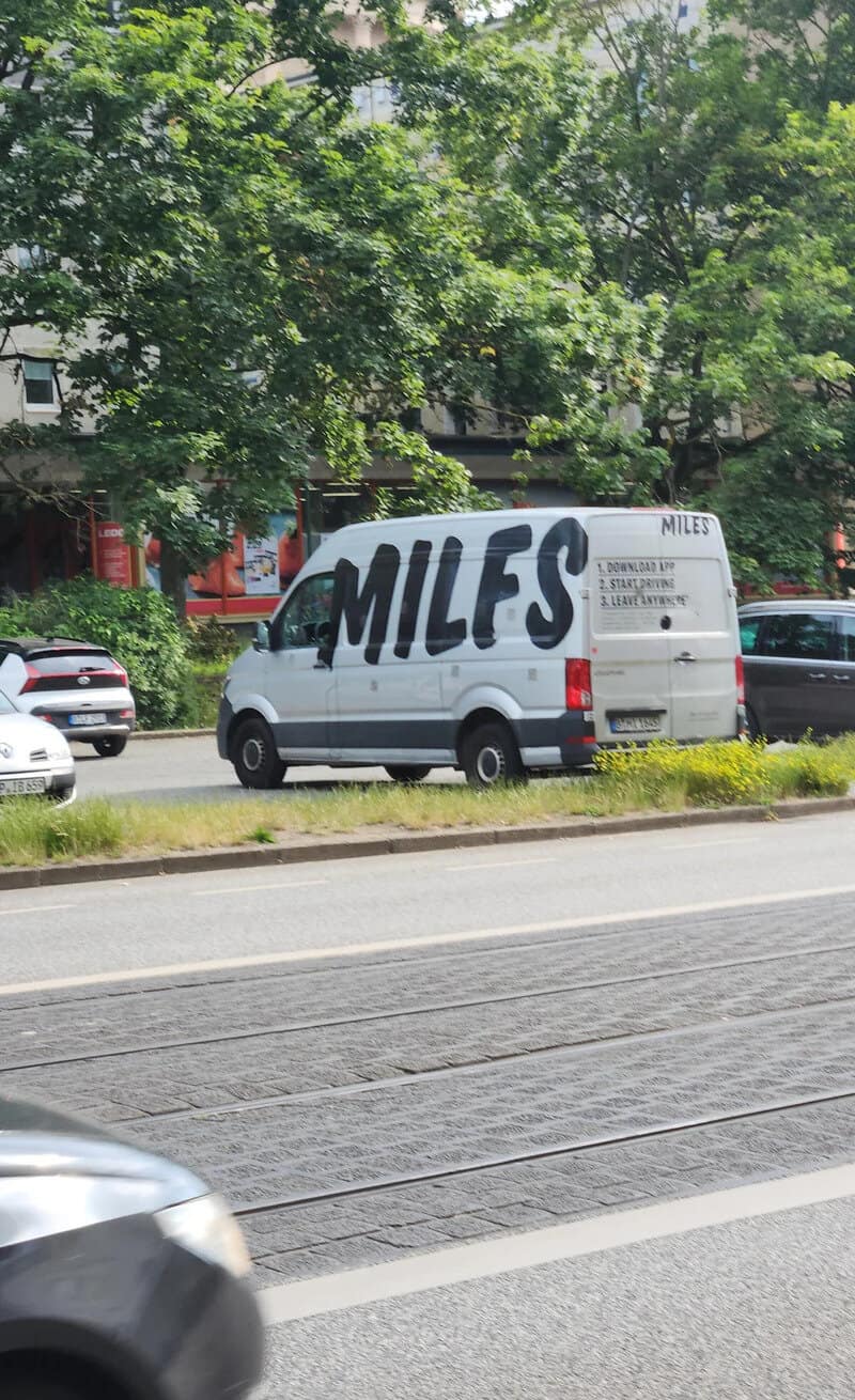White van with large black 'MILES' text on side, parked on street.
