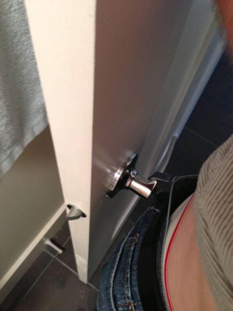 Person's waist and hand opening a door with a lock.