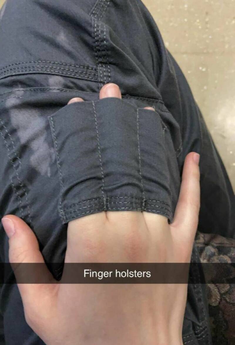 Person wearing finger holsters on their hand, with a black jacket.
