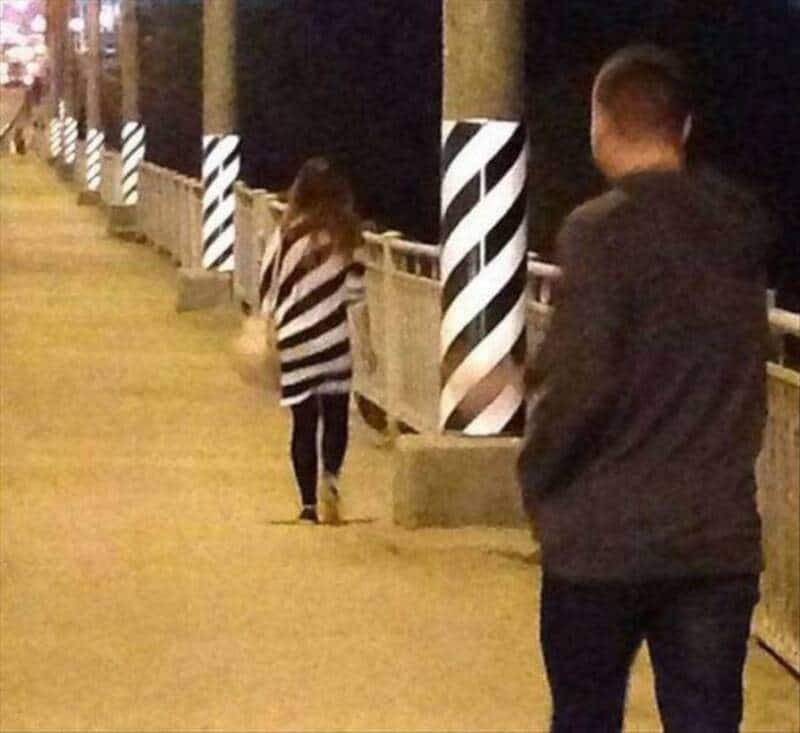 Girl in striped shirt walking away on a lit pathway at night.