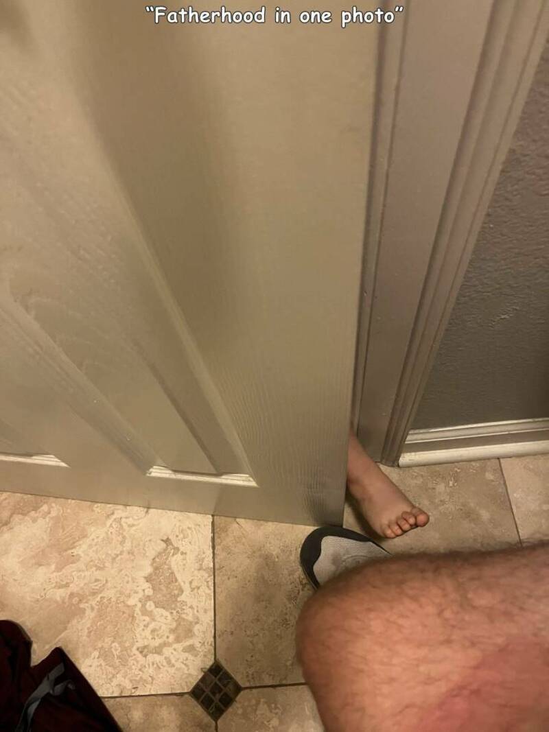 Fatherhood in one photo with a child's foot peeking out from behind a door.