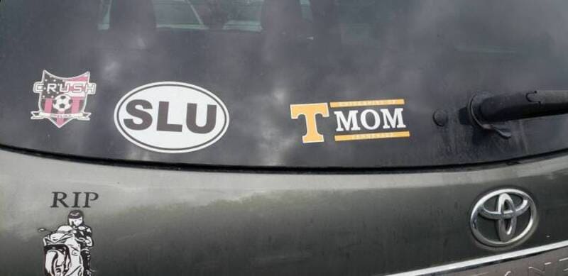 Car with stickers: 'RIP', 'SLU', 'T MOM' and a 'Rush' logo.
