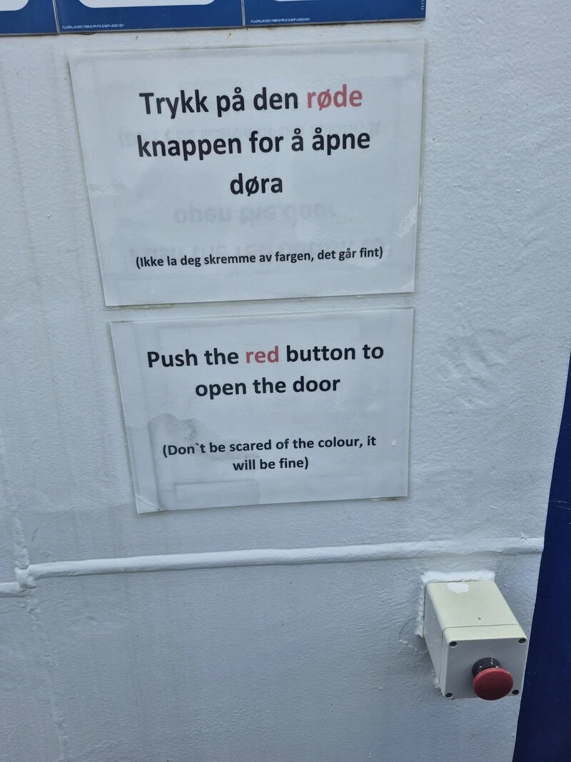 Sign instructs to push the red button to open the door, with a note about color.