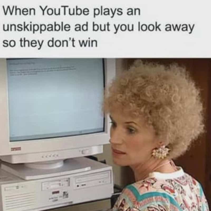 Woman with curly blonde hair looking away from computer screen with meme text about YouTube ads.