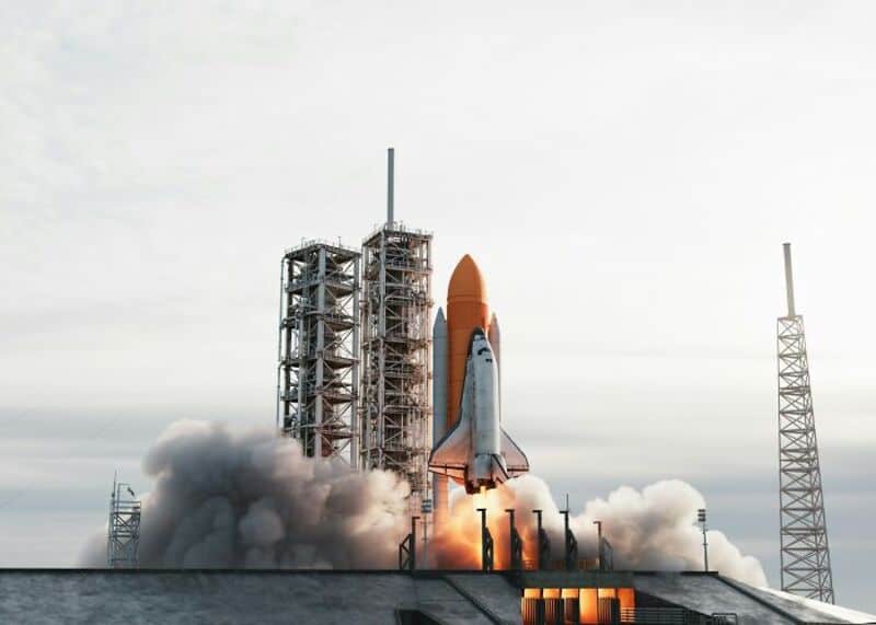 Space shuttle launch with smoke and flames at the base.