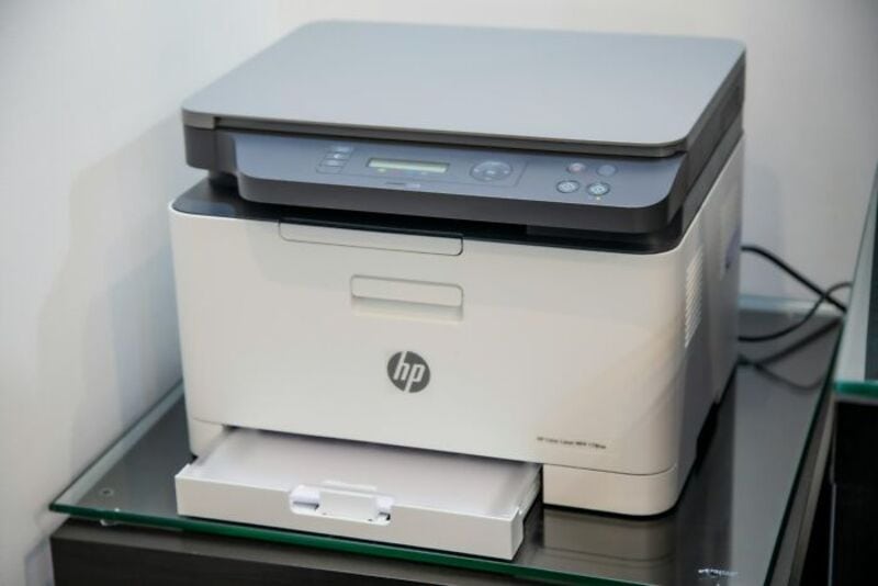HP printer on a black desk with paper tray and control panel.
