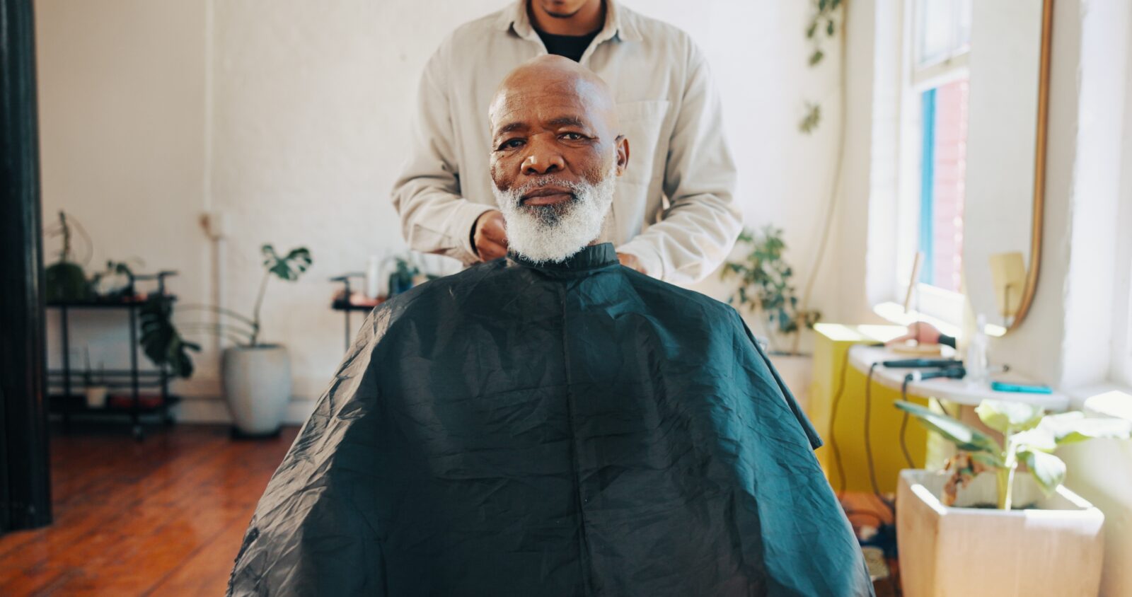 A man with a white beard getting a haircut in a bright, cozy salon.