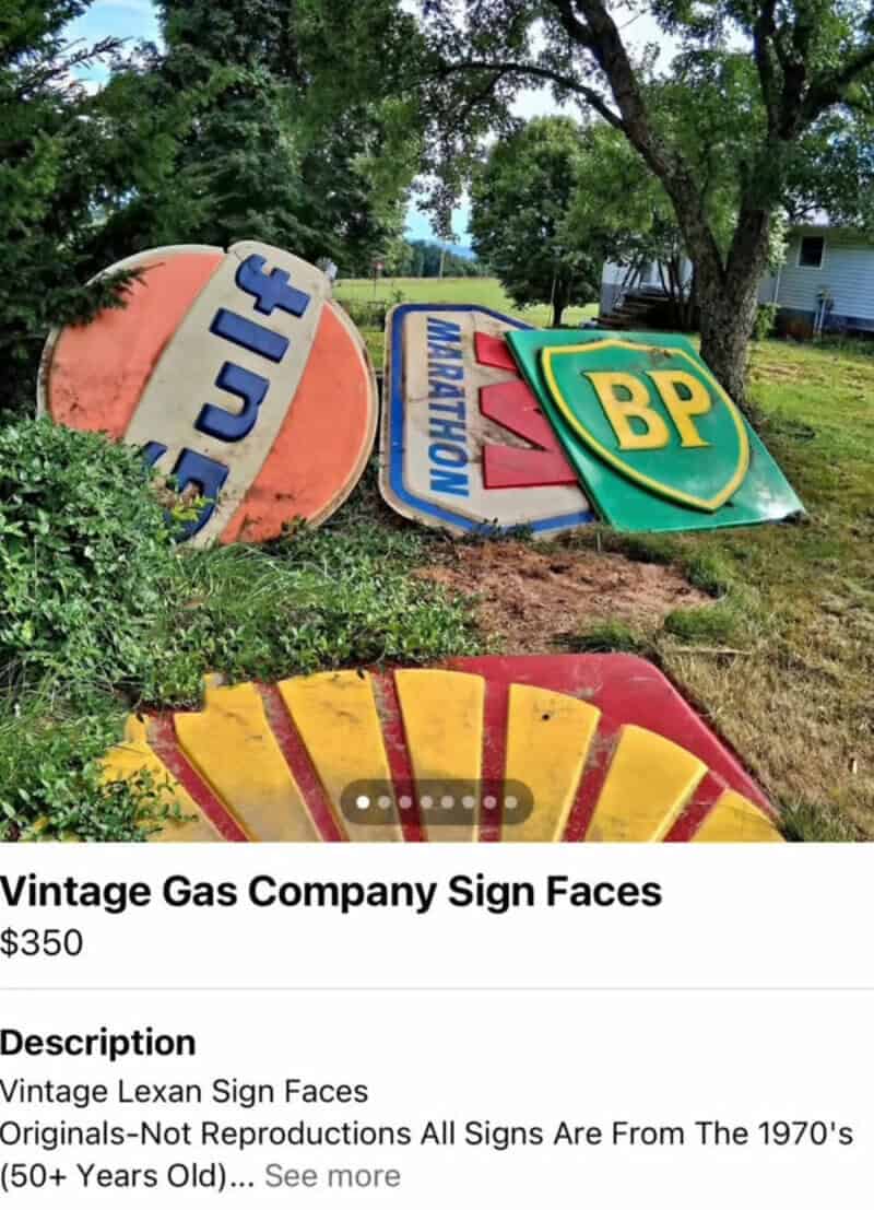 Vintage gas company signs face downward on grass, including BP, Marathon, and others.