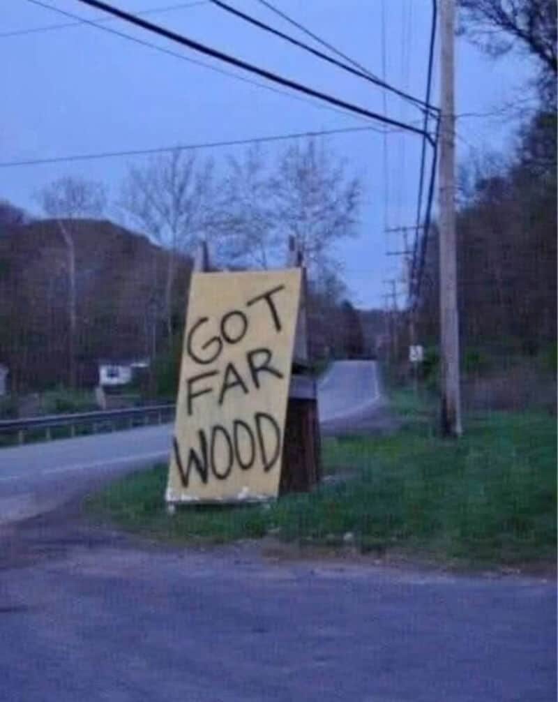 Got far wood sign on roadside with trees and power lines in background.