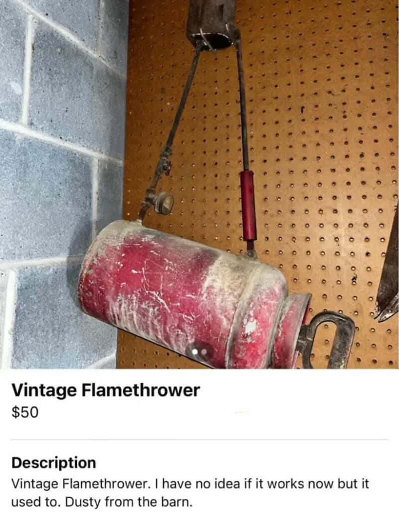 Vintage flamethrower hanging on a pegboard wall in a barn.