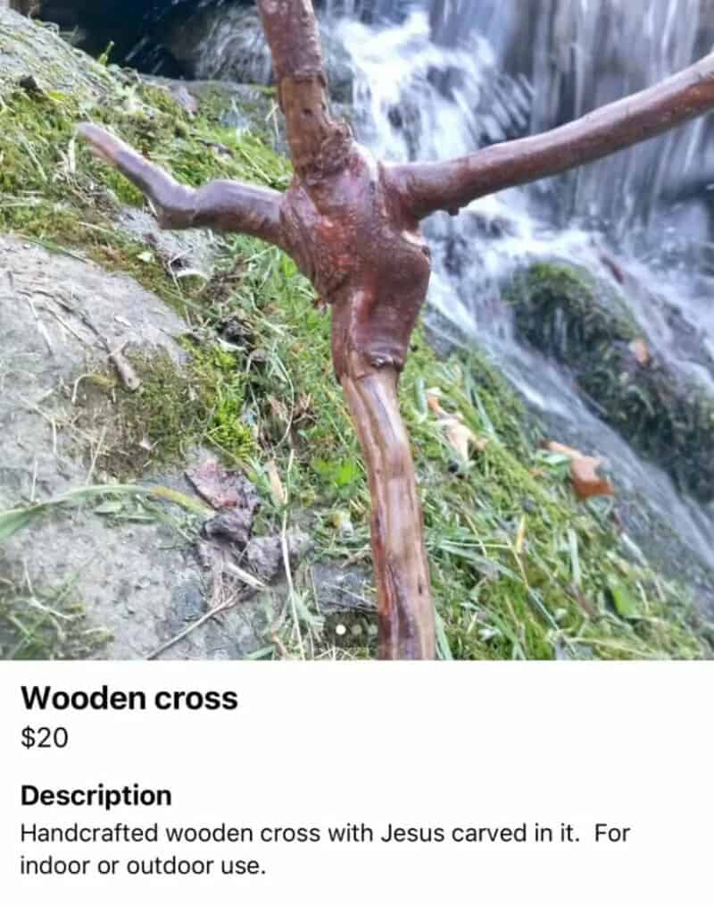Wooden cross with Jesus carved in it, placed outdoors near a waterfall.