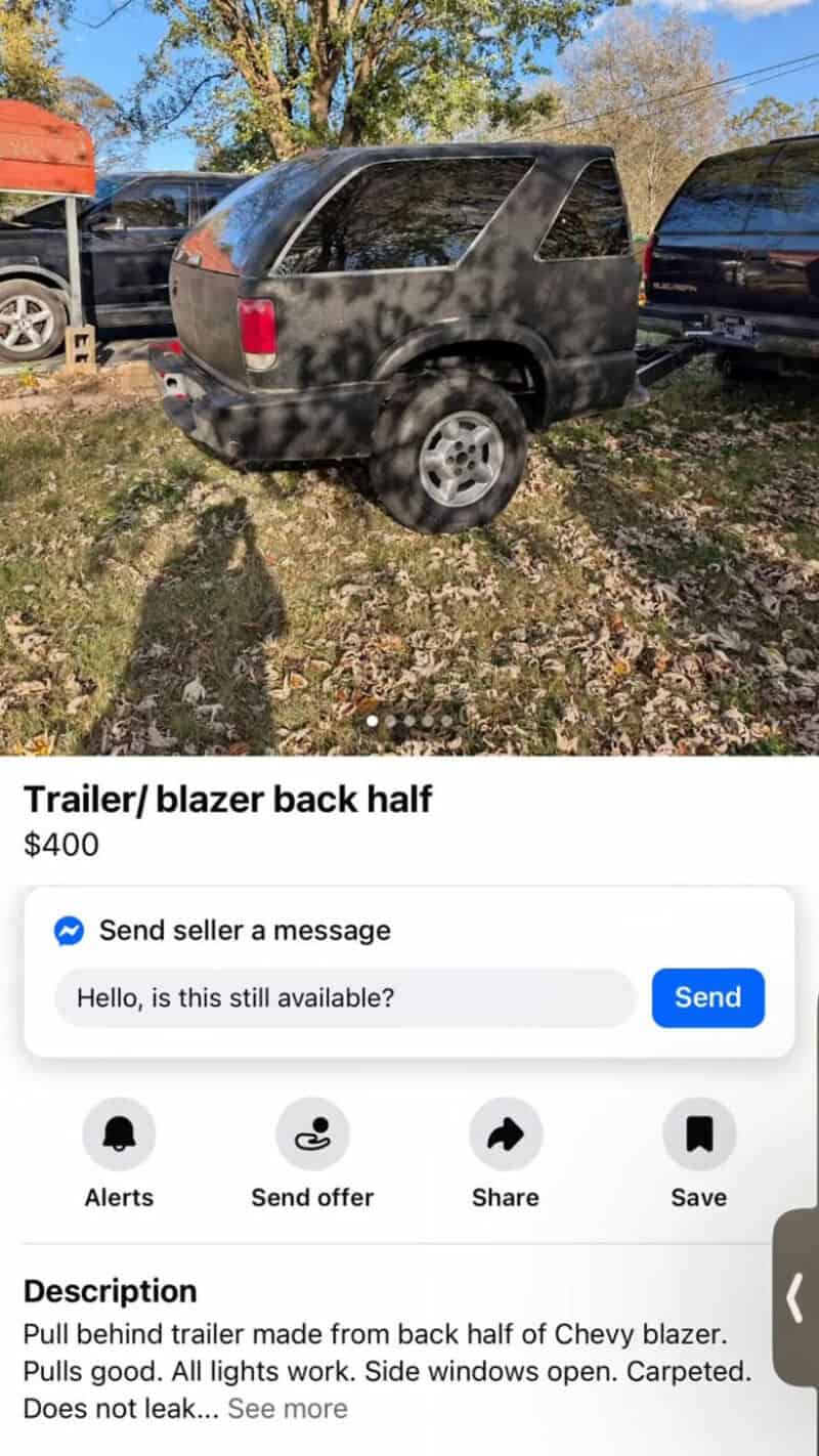 Trailer/ blazer back half, black, parked on grass with trees in background.