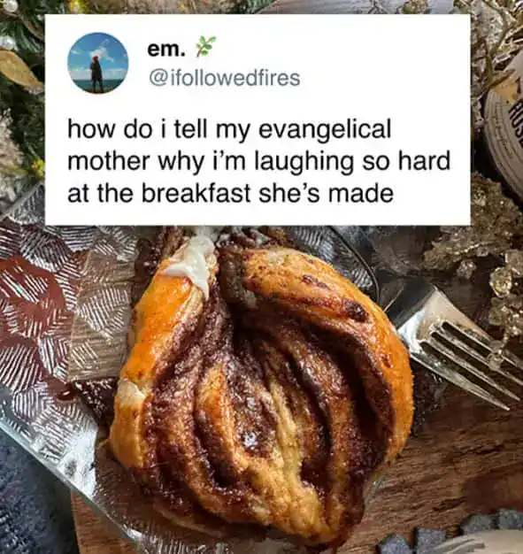 A cinnamon roll with icing on a decorative plate, with a fork beside it.