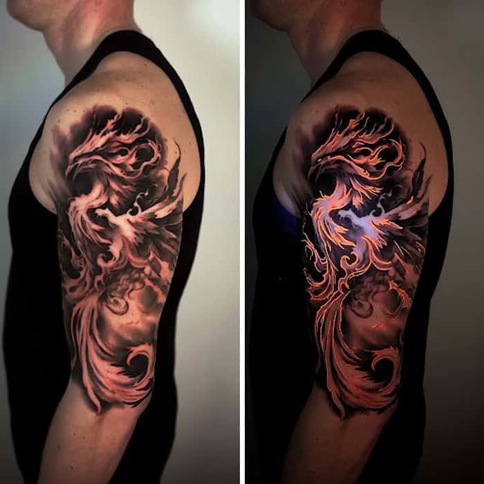 Tattoo of a fiery dragon on man's upper arm under UV light.