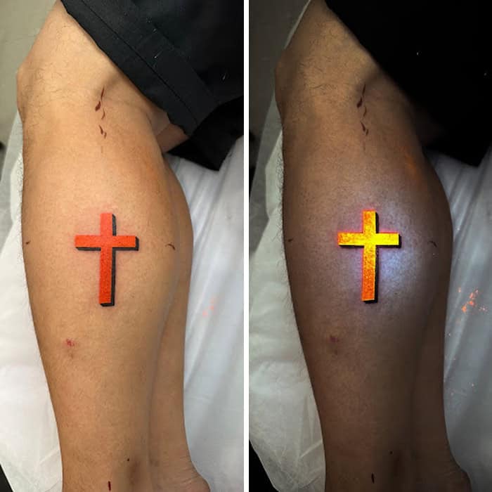 Tattoo of a cross that glows under UV light on a person's leg.