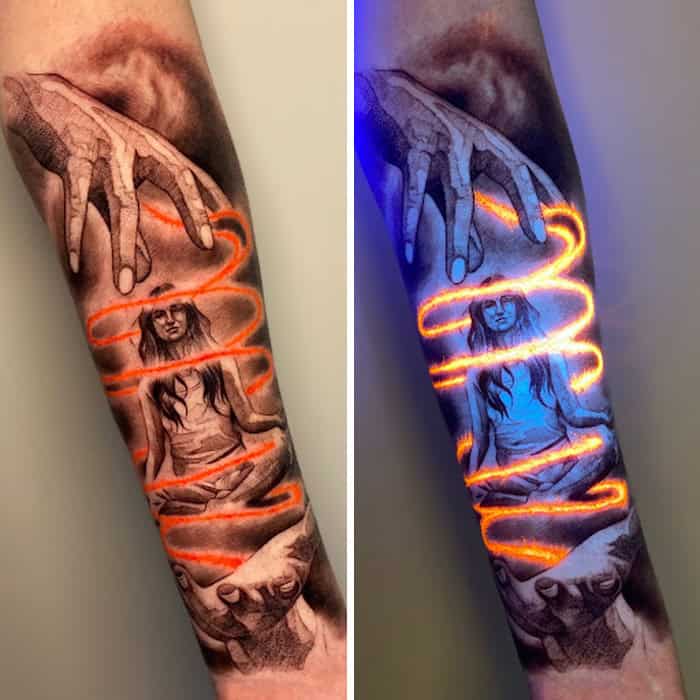 Tattoo of a woman with glowing orange UV ink and a hand above, under UV light.
