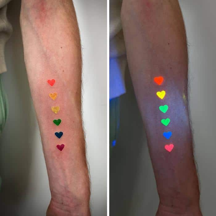 Colorful heart tattoos that glow under UV light on a person's arm.