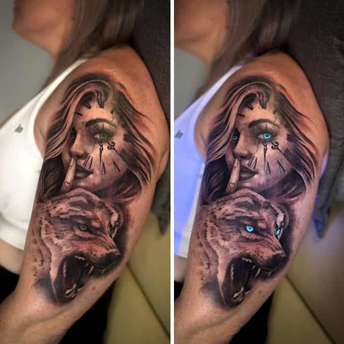Tattoo of a woman with a tiger, visible under UV light, on a person's upper arm.