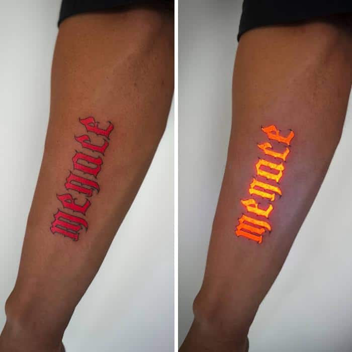 Tattoo of the word 'MERCY' in red and glow-in-the-dark orange ink.