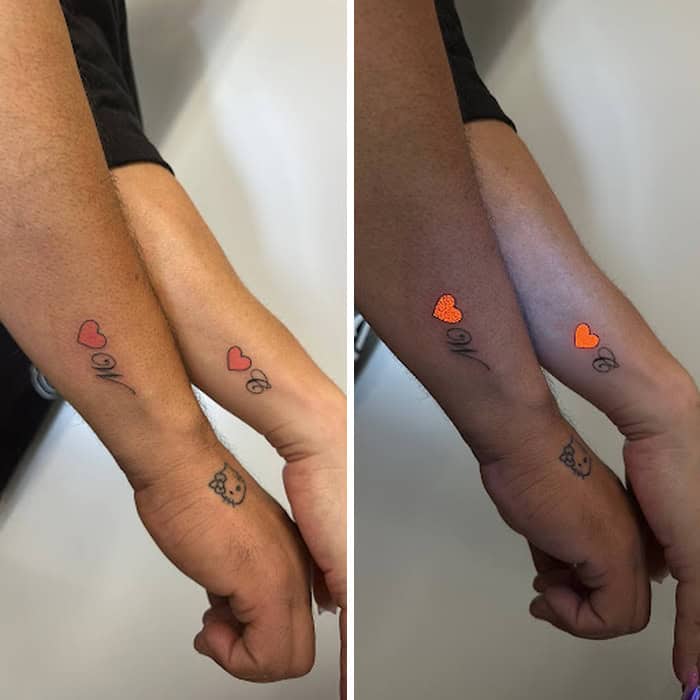 Tattooed wrist with hearts and a Hello Kitty design, shown under UV light.