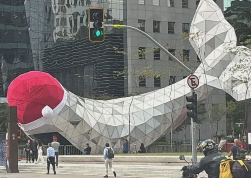 Santa hat on a large, geometric whale sculpture in an urban setting.