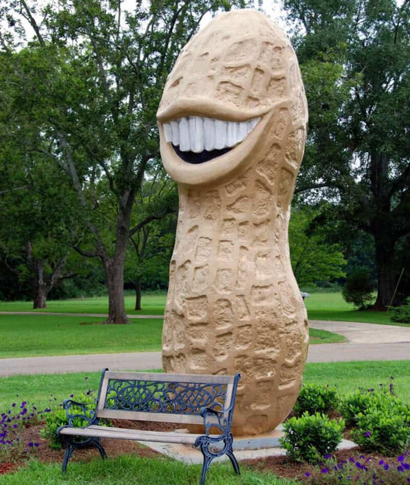 Large whimsical sculpture of a smiling face with big teeth in a park setting.
